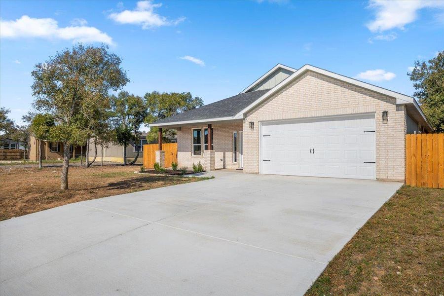 Ranch-style home featuring brick siding, concrete driveway, an attached garage, and covered porch
