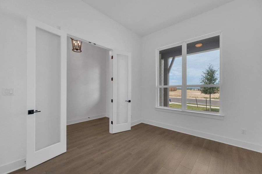 Spare room with dark wood-type flooring and a chandelier Spare room with dark wood-type flooring and a chandelier