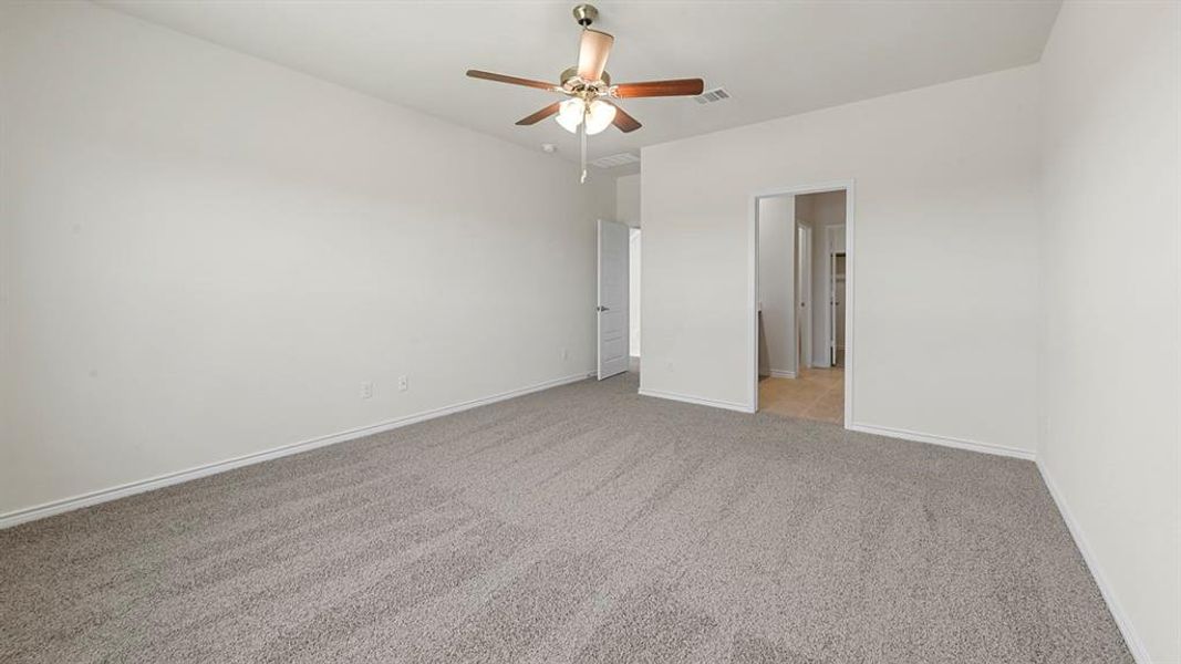 Spacious room featuring neutral carpeting, light-colored walls, and a ceiling fan with integrated lighting