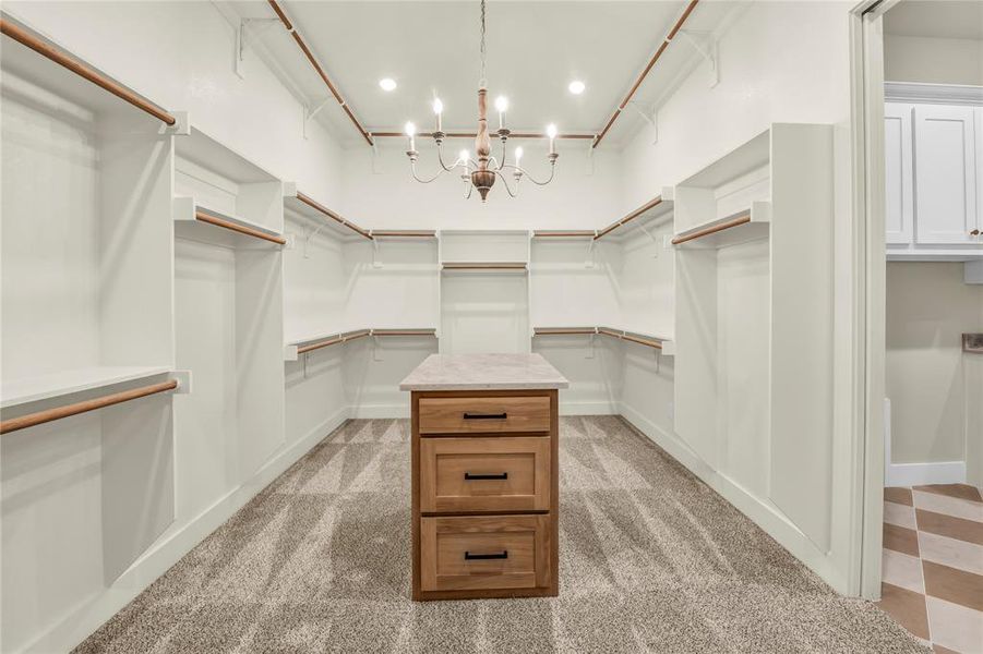 Walk in closet with light carpet and a chandelier