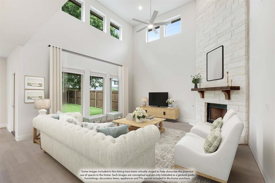 Living room with two-story ceiling, stone fireplace, ceiling fan, and French doors leading to backyard Living room with two-story ceiling, stone fireplace, ceiling fan, and French doors leading to backyard