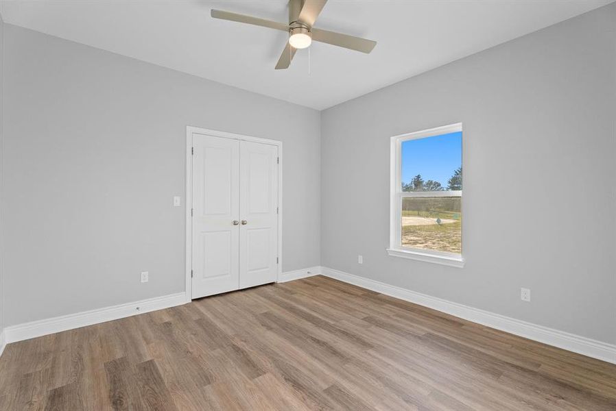Unfurnished bedroom with light wood-style floors, ceiling fan, and a closet