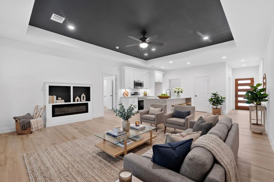 Spacious living area featuring a tray ceiling with a dark accent, recessed lighting, and a ceiling fan Spacious living area featuring a tray ceiling with a dark accent, recessed lighting, and a ceiling fan