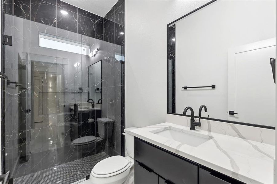 Bathroom with toilet, vanity, and a shower with shower door