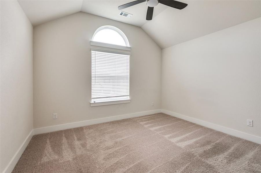Carpeted spare room featuring a ceiling fan, vaulted ceiling, and baseboards Carpeted spare room featuring a ceiling fan, vaulted ceiling, and baseboards