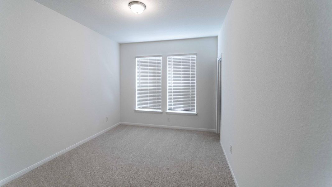 Empty room with light colored carpet and baseboards