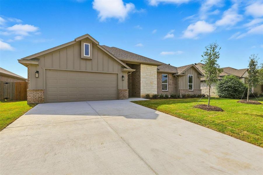 View of front of property with board and batten siding, concrete driveway, a front lawn, and a garage View of front of property with board and batten siding, concrete driveway, a front lawn, and a garage