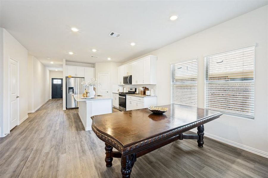 Open-concept living space featuring wood-finish flooring, recessed lighting, and crisp white walls Open-concept living space featuring wood-finish flooring, recessed lighting, and crisp white walls