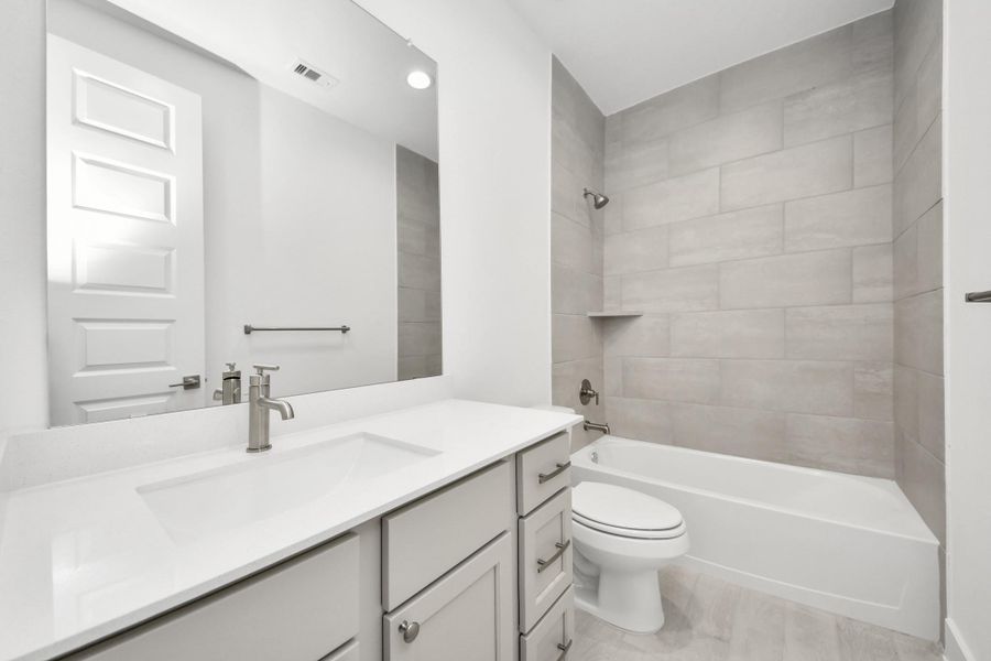 Secondary bath features tile flooring, bath/shower combo with tile surround, light stained wood cabinets, beautiful light countertop. Secondary bath features tile flooring, bath/shower combo with tile surround, light stained wood cabinets, beautiful light countertop.