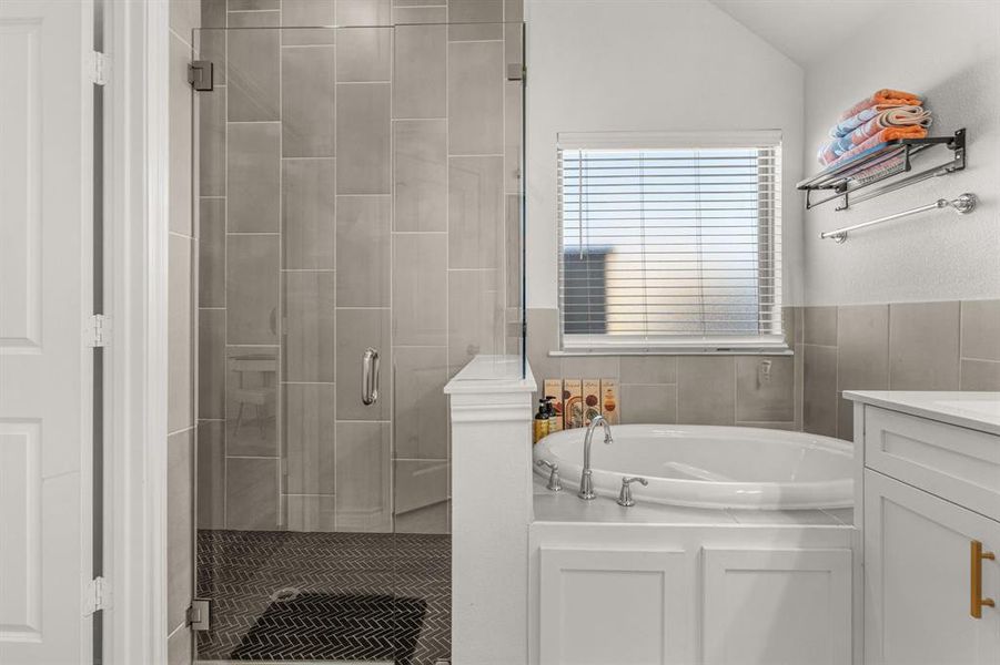 Bathroom featuring vanity, plus walk in shower, and vaulted ceiling