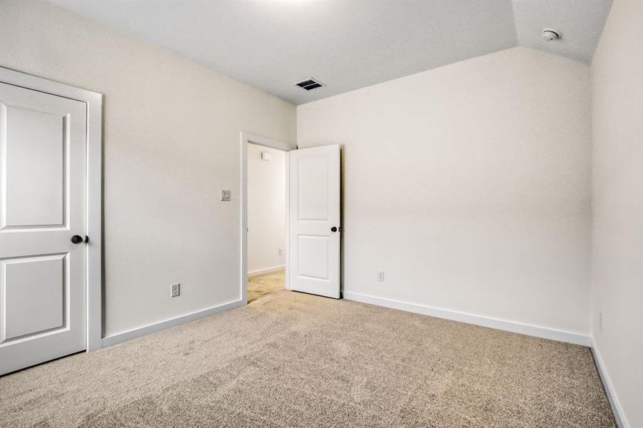 Unfurnished bedroom with carpet and lofted ceiling