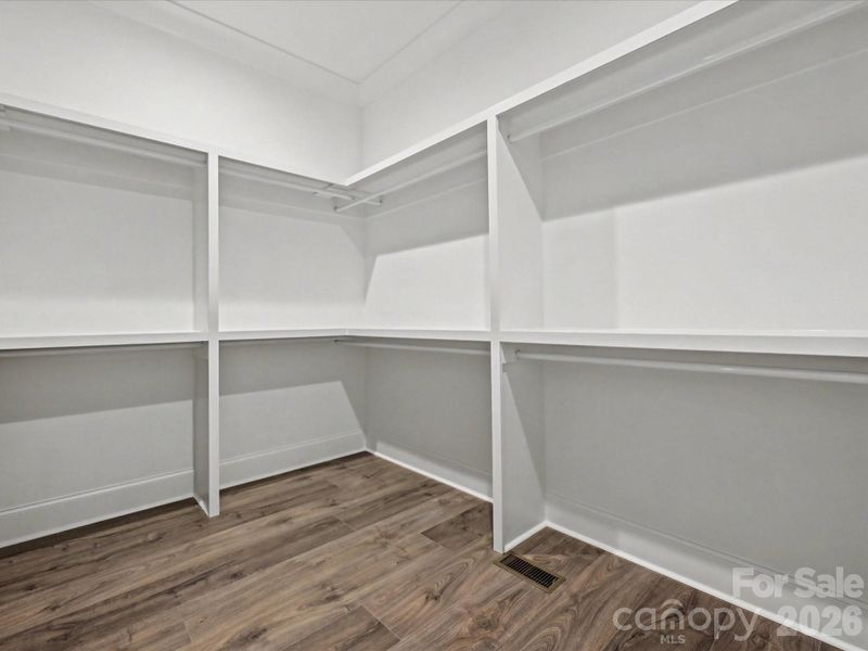 Spacious walk-in closet with built-in shelving and abundant hanging space, offering excellent organization and storage.