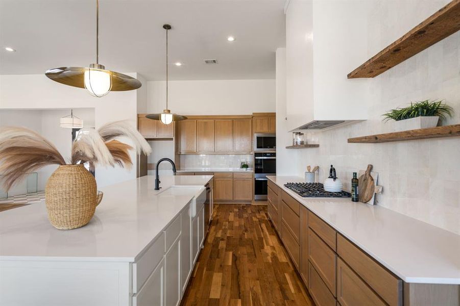 Kitchen featuring dark wood-type flooring, sink, decorative light fixtures, stainless steel appliances, and decorative backsplash