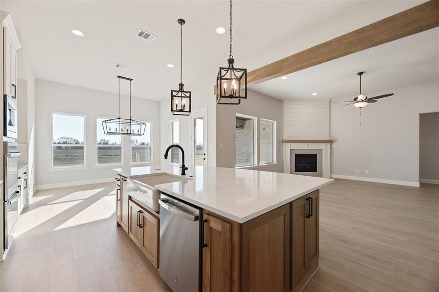 Kitchen featuring recessed lighting, a fireplace, stainless steel appliances, hanging light fixtures, and a center island with sink Kitchen featuring recessed lighting, a fireplace, stainless steel appliances, hanging light fixtures, and a center island with sink