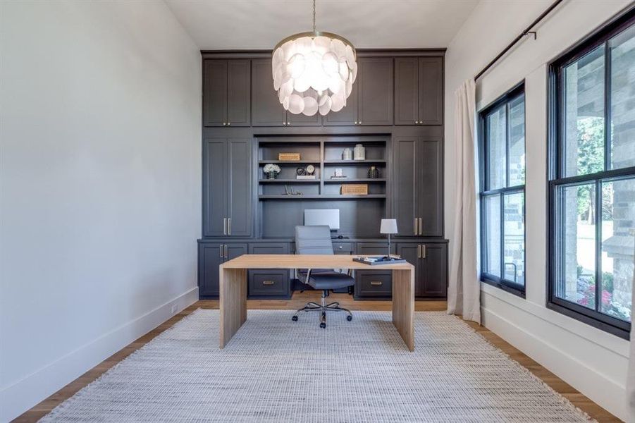 Office space with a chandelier and light wood-type flooring Office space with a chandelier and light wood-type flooring