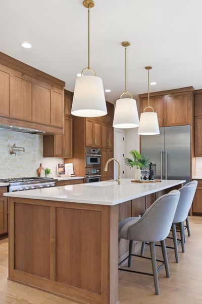 Kitchen featuring backsplash, brown cabinets, light wood-type flooring, and hanging light fixtures