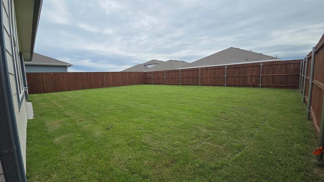 Expansive backyard featuring a lush lawn and perimeter wood fencing Expansive backyard featuring a lush lawn and perimeter wood fencing