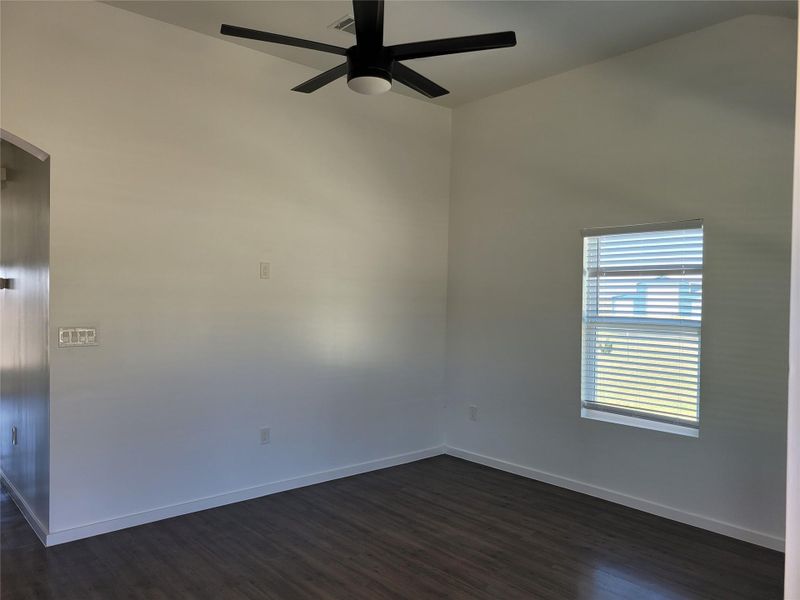 A versatile room features rich wood flooring, high ceilings, and a modern ceiling fan, ready for personal touches. A versatile room features rich wood flooring, high ceilings, and a modern ceiling fan, ready for personal touches.