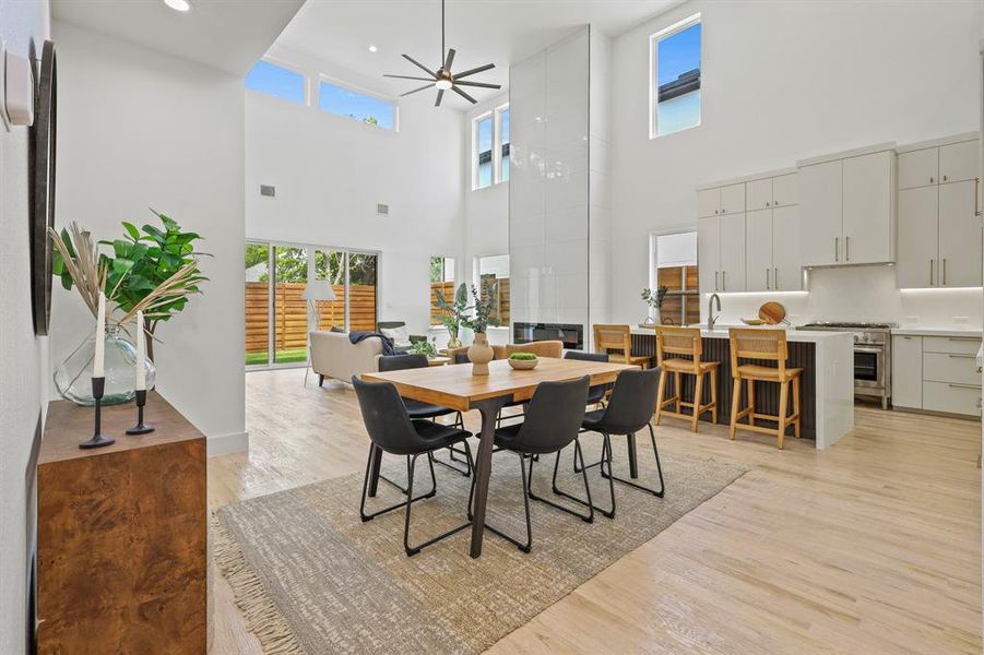 Dining area featuring ceiling fan, sink, a high ceiling, and light hardwood / wood-style floors