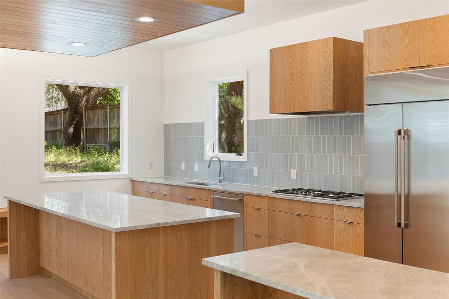 Kitchen with stainless steel appliances, modern cabinets, light stone counters, recessed lighting, and healthy amount of natural light Kitchen with stainless steel appliances, modern cabinets, light stone counters, recessed lighting, and healthy amount of natural light