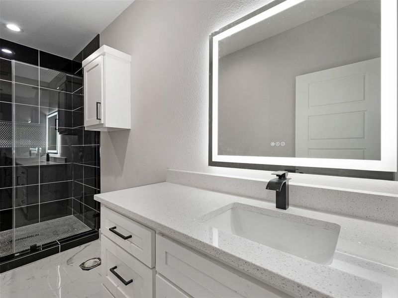 Bathroom with tiled shower and vanity