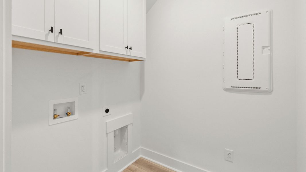 Convenient laundry room with cabinetry at Chestnut Farms by DRB Homes