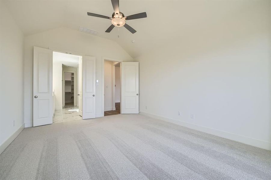 Unfurnished bedroom with visible vents, baseboards, light colored carpet, and vaulted ceiling