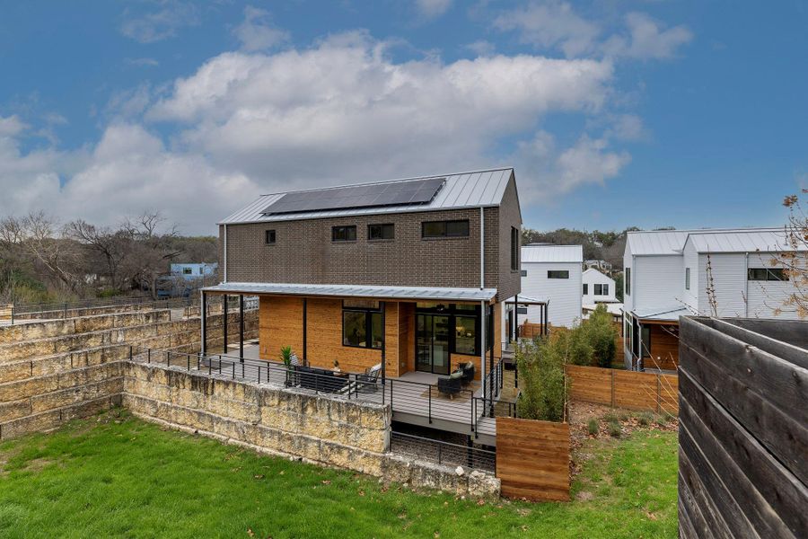 Back of property featuring solar panels, a lawn, a standing seam roof, metal roof, and a fenced backyard