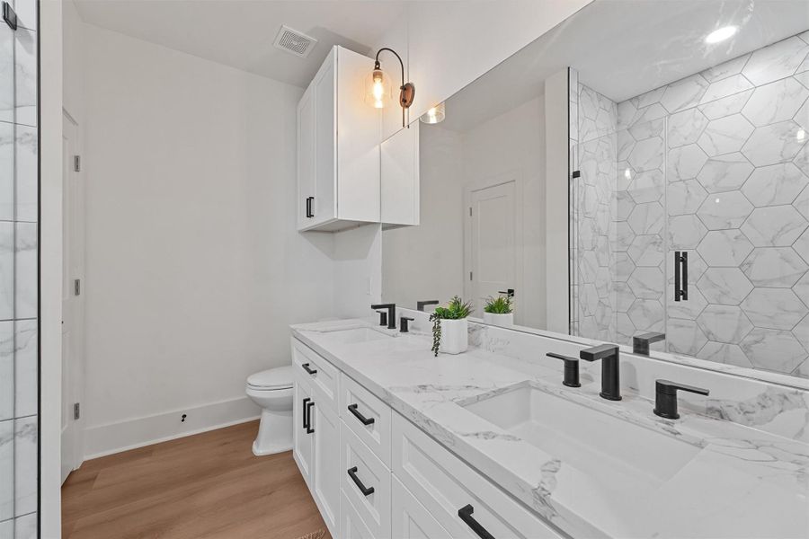 Attached ensuite bathroom with double vanities, walk-in shower, and thoughtful finishes that mirror the home’s upscale design. Attached ensuite bathroom with double vanities, walk-in shower, and thoughtful finishes that mirror the home’s upscale design.
