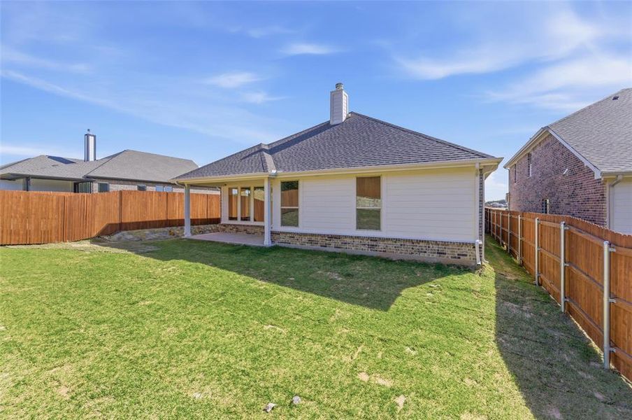 Rear view of house with a patio area, brick siding, a fenced backyard, and a shingled roof