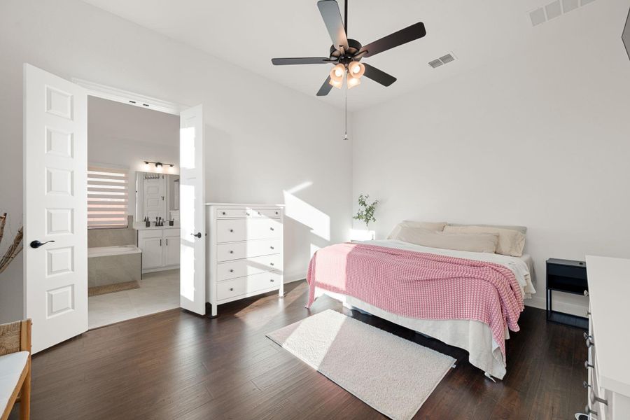 Elegant primary bedroom offers French doors opening to a tranquil private bathroom. Elegant primary bedroom offers French doors opening to a tranquil private bathroom.