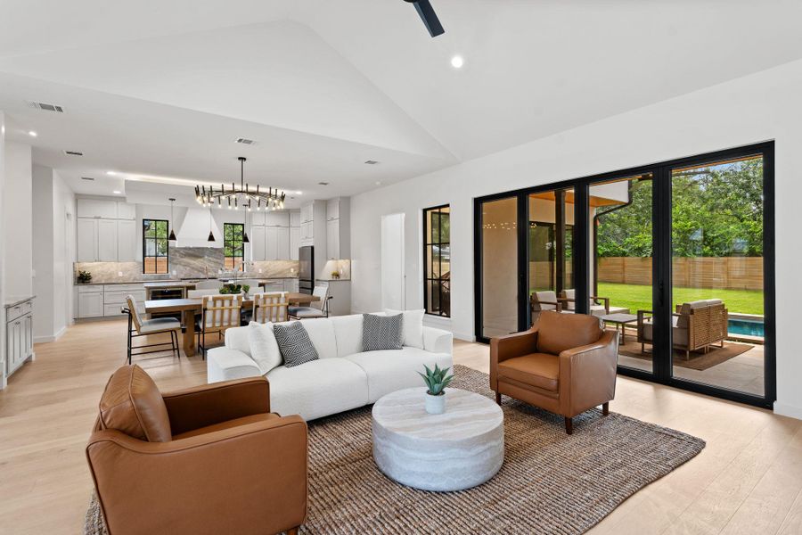 Bright, open-concept living space with vaulted ceilings, a contemporary kitchen, and expansive glass doors opening to the backyard. Bright, open-concept living space with vaulted ceilings, a contemporary kitchen, and expansive glass doors opening to the backyard.