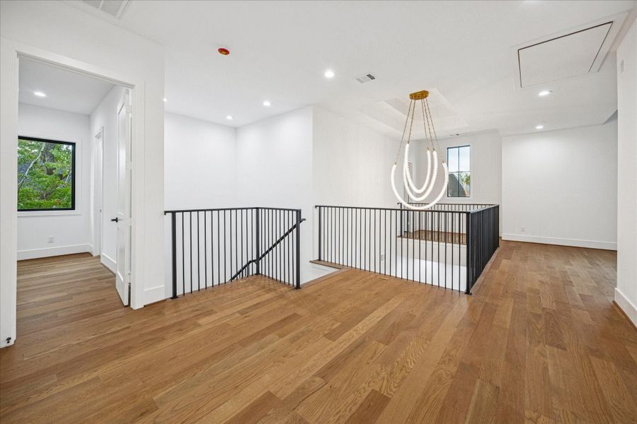 Soaring ceilings and an elegant tiered chandelier set a refined tone on the upper landing. Clean lines from the iron balustrade complement wide plank floors, while large picture windows fill the space with natural light. A true architectural pause between the private and social areas of the home. Soaring ceilings and an elegant tiered chandelier set a refined tone on the upper landing. Clean lines from the iron balustrade complement wide plank floors, while large picture windows fill the space with natural light. A true architectural pause between the private and social areas of the home.