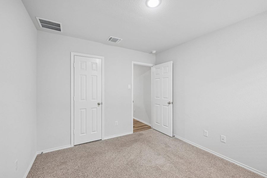 Carpeted room featuring light gray walls, white trim, and a white six-panel door