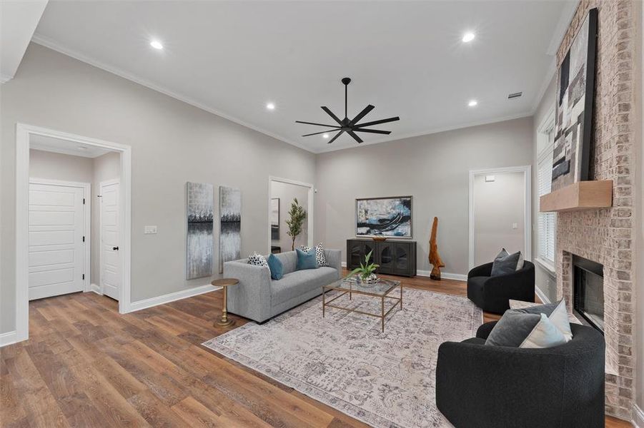 Living room with a ceiling fan, recessed lighting, wood finished floors, and a fireplace