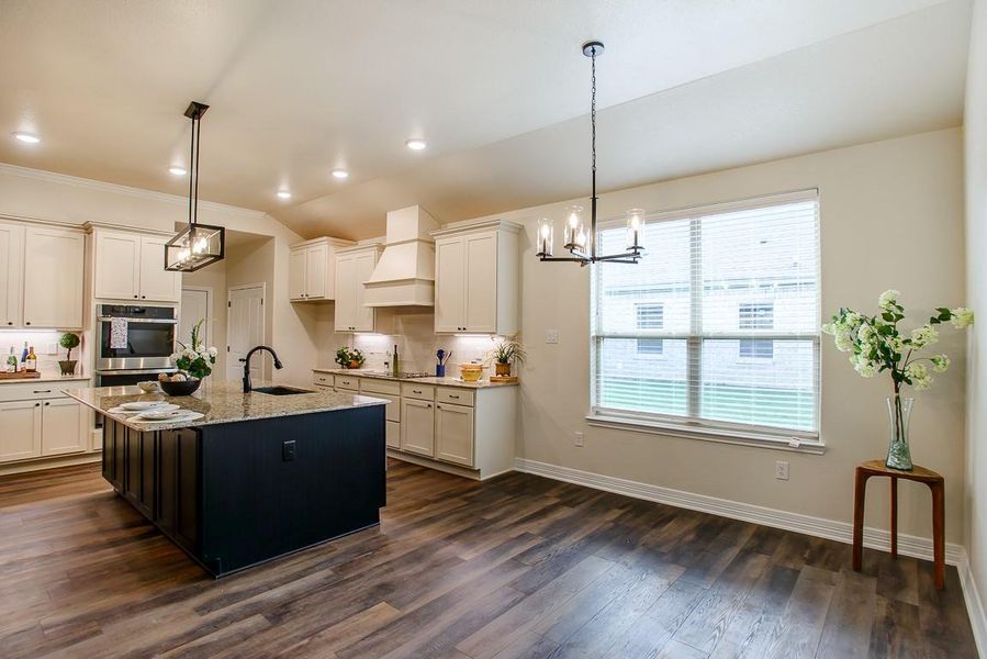 Kitchen with backsplash, a chandelier, light stone counters, dark wood-style floors, and stainless steel double oven Kitchen with backsplash, a chandelier, light stone counters, dark wood-style floors, and stainless steel double oven