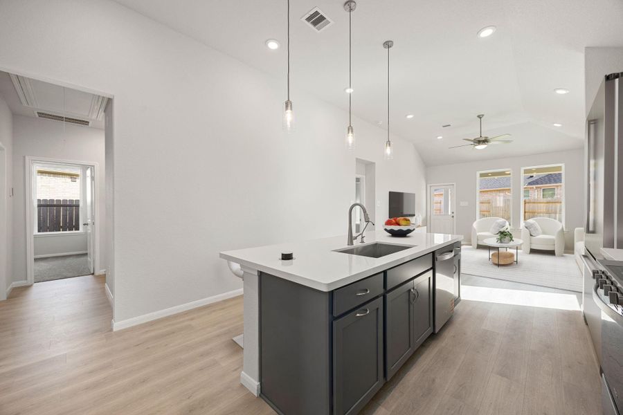 The generously sized kitchen island, central to this open-concept space, features sleek, dark gray cabinetry and a clean white countertop. A modern, integrated pop-up charging station and electrical hub provide convenient, discreet power access for devices and small appliances, ensuring a clutter-free and functional workspace for everyday living and entertaining. The generously sized kitchen island, central to this open-concept space, features sleek, dark gray cabinetry and a clean white countertop. A modern, integrated pop-up charging station and electrical hub provide convenient, discreet power access for devices and small appliances, ensuring a clutter-free and functional workspace for everyday living and entertaining.
