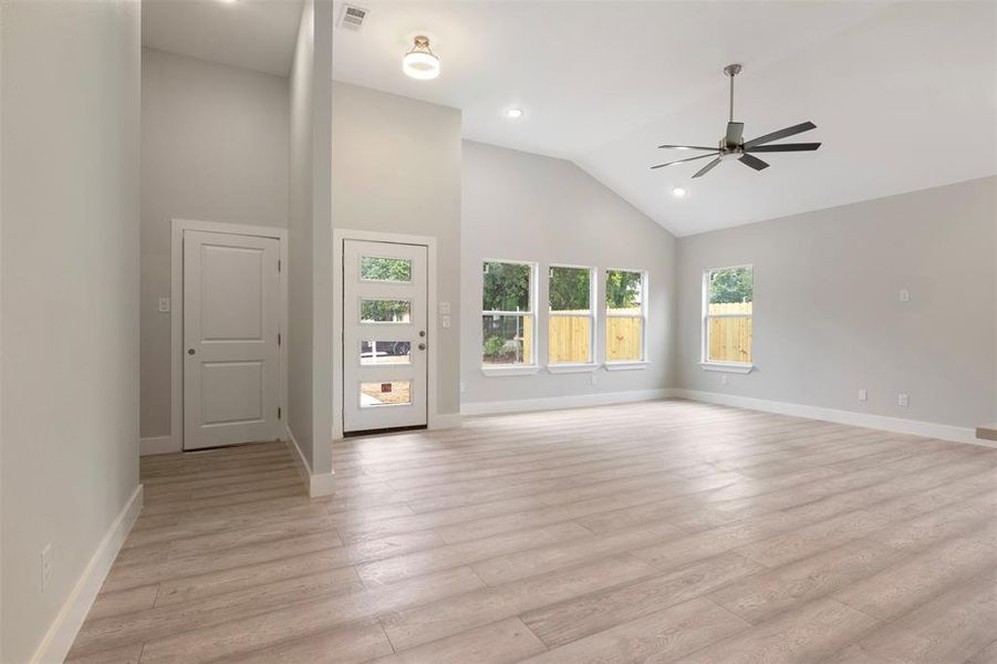 Unfurnished living room with high vaulted ceiling, ceiling fan, and light hardwood / wood-style flooring