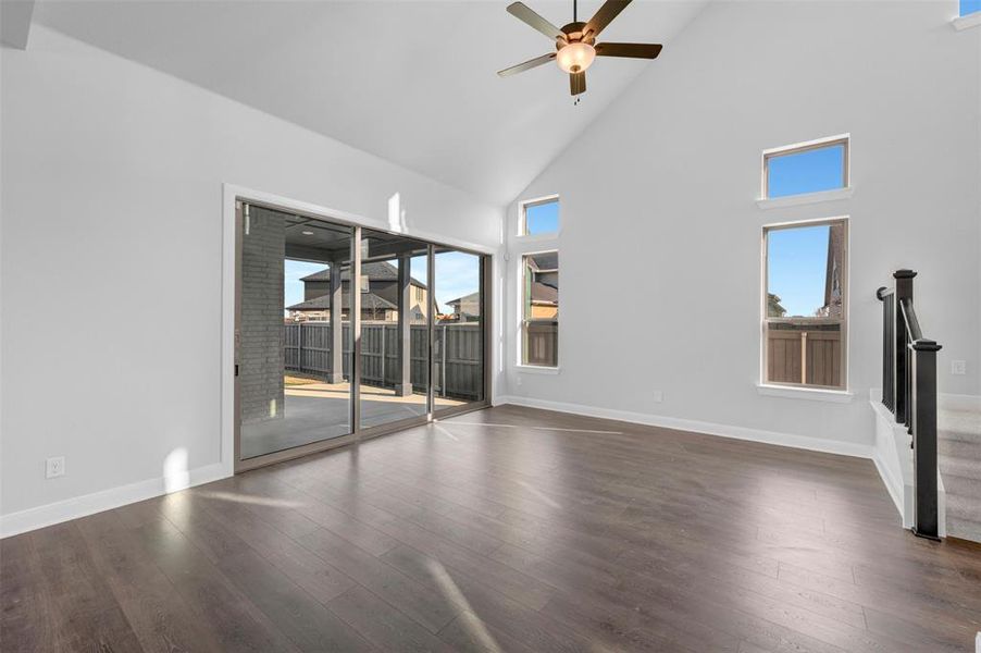 Unfurnished room with a ceiling fan, dark wood-style floors, and lofted ceiling Unfurnished room with a ceiling fan, dark wood-style floors, and lofted ceiling