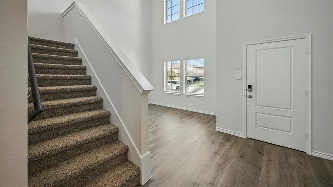 Entrance foyer featuring plenty of natural light, stairway, wood finished floors, and a high ceiling Entrance foyer featuring plenty of natural light, stairway, wood finished floors, and a high ceiling