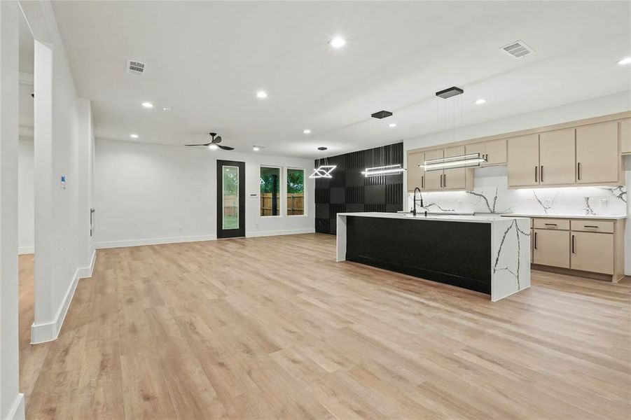 Kitchen featuring recessed lighting, light wood-style floors, pendant lighting, light stone counters, and open floor plan Kitchen featuring recessed lighting, light wood-style floors, pendant lighting, light stone counters, and open floor plan