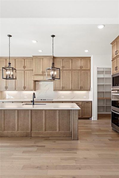 Kitchen with a notable chandelier, sink, decorative light fixtures, and light hardwood / wood-style floors