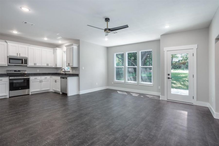 Kitchen featuring appliances with stainless steel finishes, white cabinets, dark wood finished floors, healthy amount of natural light, and recessed lighting Kitchen featuring appliances with stainless steel finishes, white cabinets, dark wood finished floors, healthy amount of natural light, and recessed lighting
