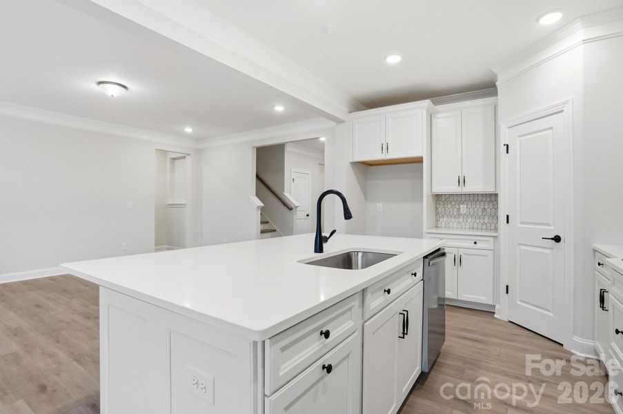 Kitchen features white cabinets, black hardware and quartz countertops