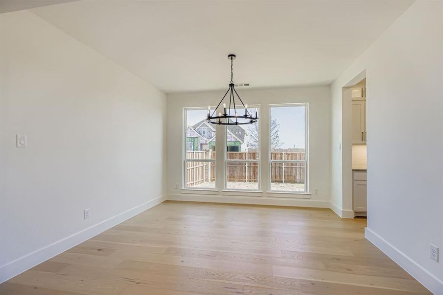 Unfurnished dining area with light wood finished floors and a chandelier Unfurnished dining area with light wood finished floors and a chandelier