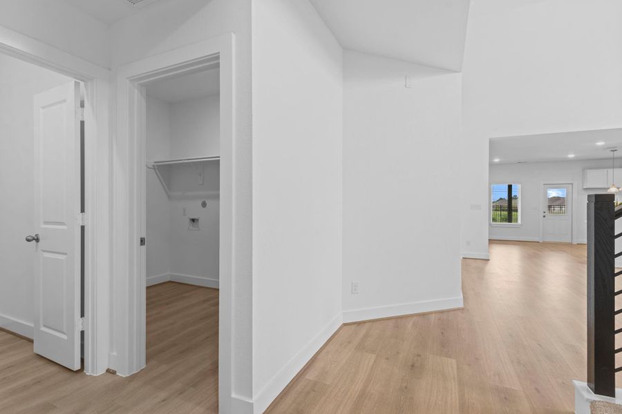 A beautifully designed hallway opens to the main living area, with a glimpse of soaring ceilings and dramatic windows ahead. To the left, you’ll find convenient access to the powder bathroom and utility room—thoughtfully positioned for everyday functionality while maintaining a clean, cohesive flow. Look at those gorgeous floors!  Beautiful wood-like tile flooring! **Image Representative of Plan Only and May Vary as Built**.