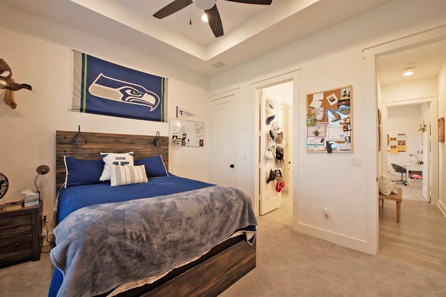 Bedroom featuring light colored carpet, ceiling fan, and a tray ceiling