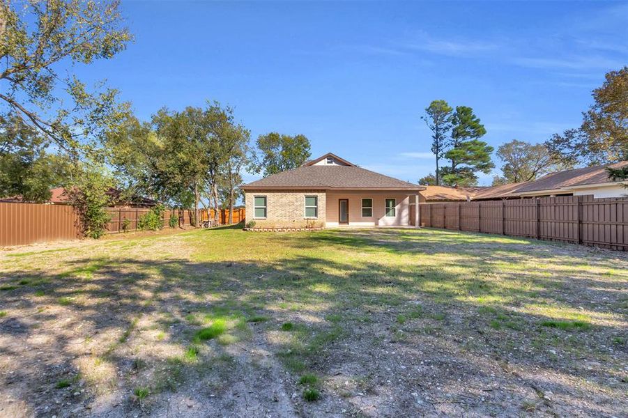 Back of house with a fenced backyard and a patio area