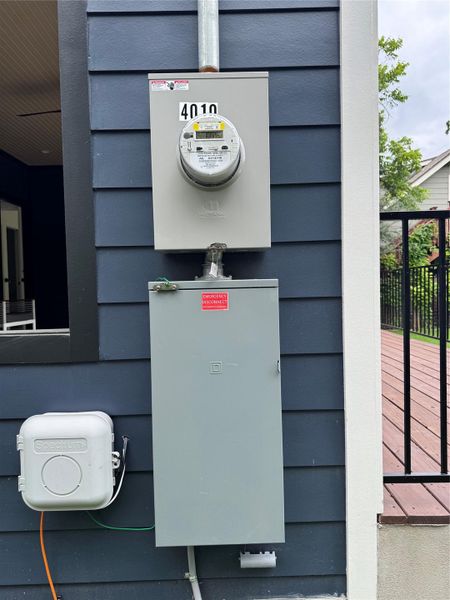 Exterior utility installations featuring a dark blue horizontal siding, a residential electrical meter, and a separate electrical service panel