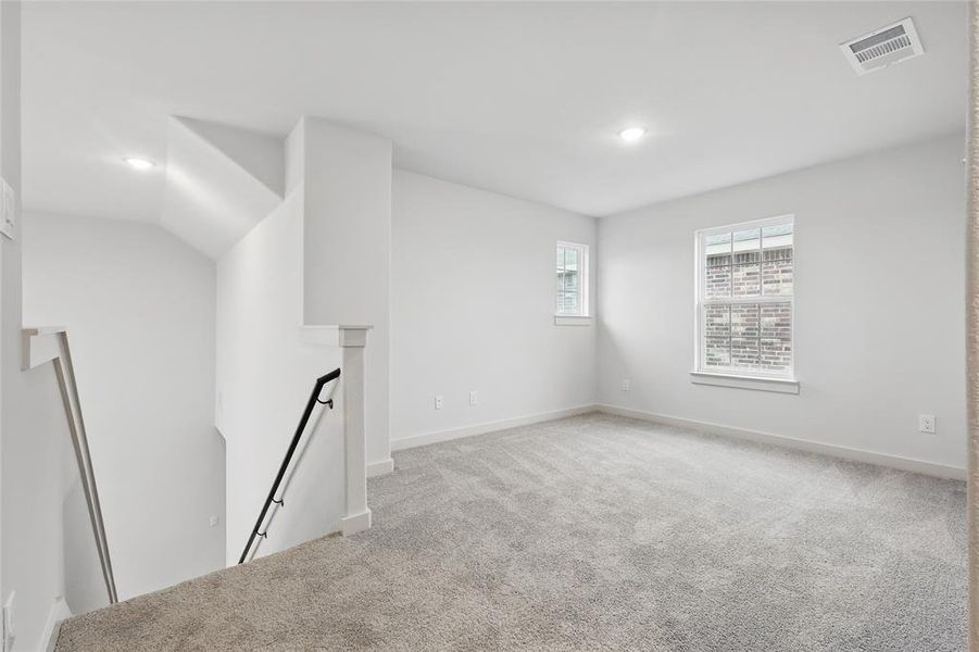 Empty room with light carpet and recessed lighting